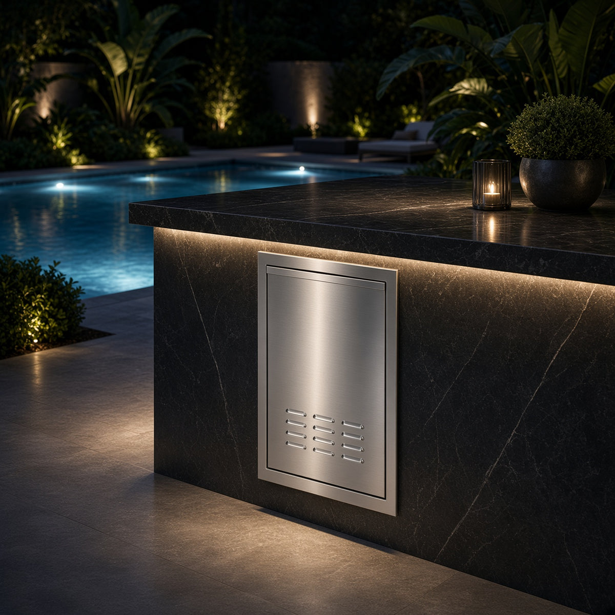 AMG 18-Inch Deluxe Trash or Fuel Pull-Out Drawer installed in a poolside outdoor kitchen island at night