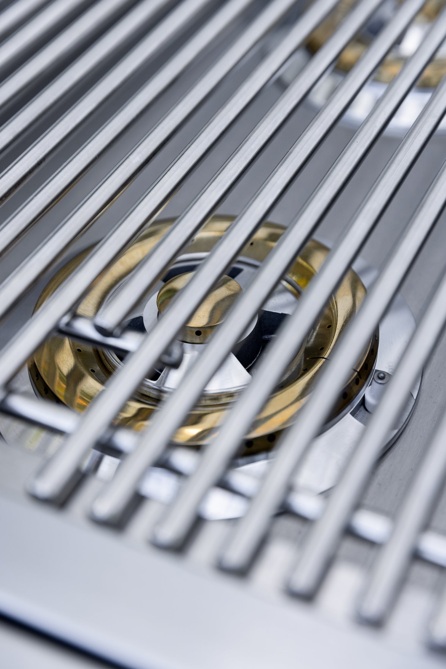 Atlas Double Side Burner, close-up of brass burner beneath cooking grates
